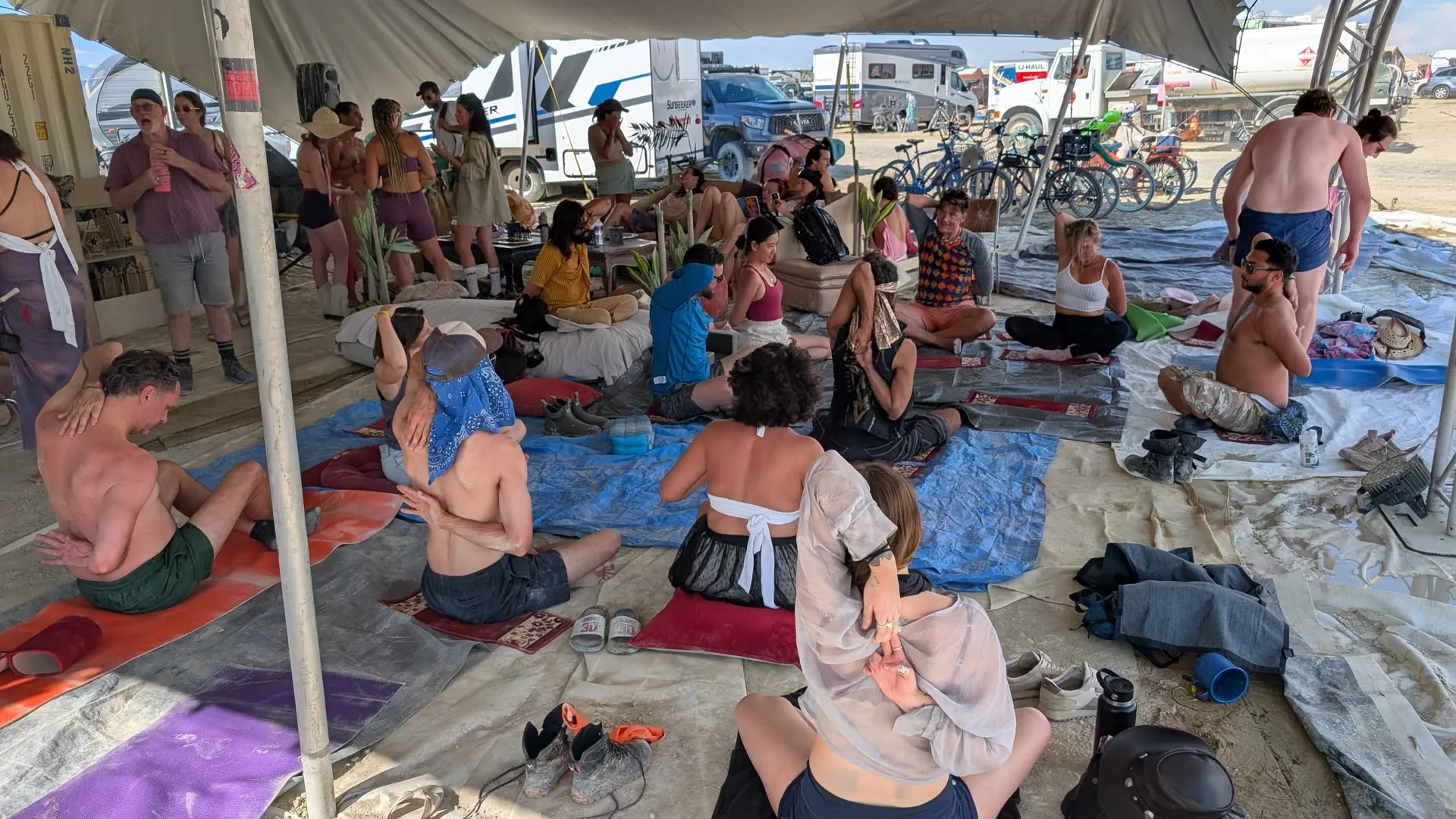 A shaded yoga and breathwork class with campers seated on mats and cushions.